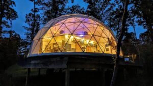 Geodesic glamping dome lit up at night, lodging near The Caverns for CaveFest 2026