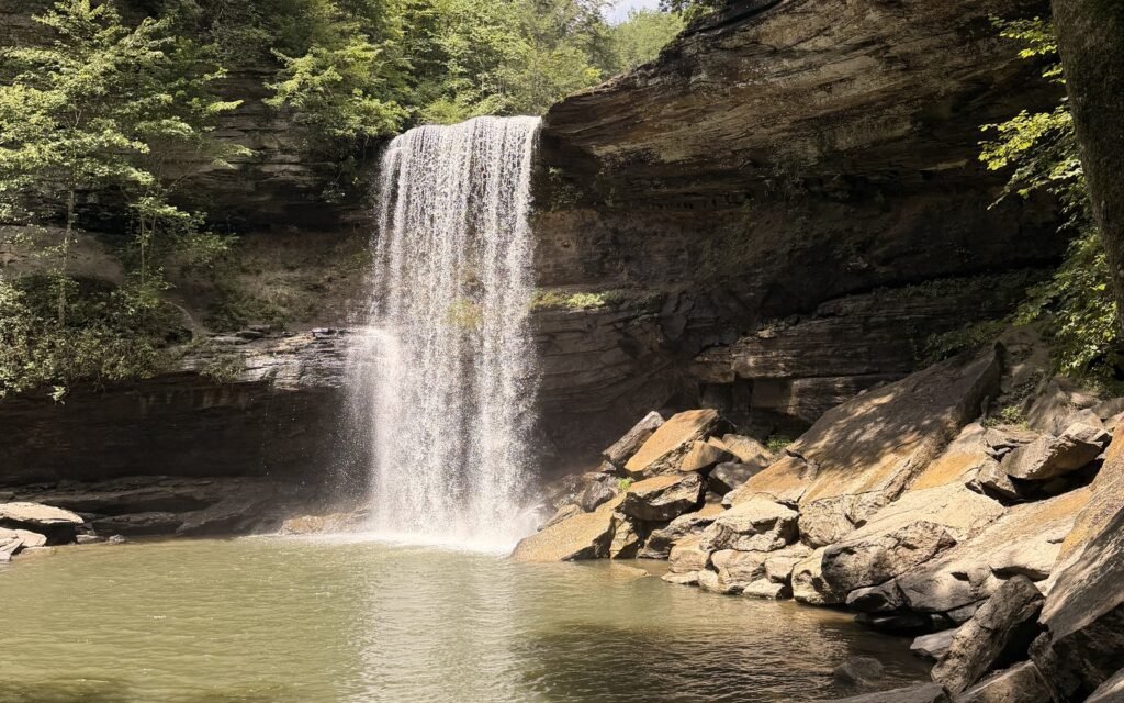 Lower Greeter Falls, a 50-foot waterfall pouring into a green pool below sandstone bluffs in Tennessee