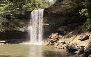 Lower Greeter Falls, a 50-foot waterfall pouring into a green pool below sandstone bluffs in Tennessee